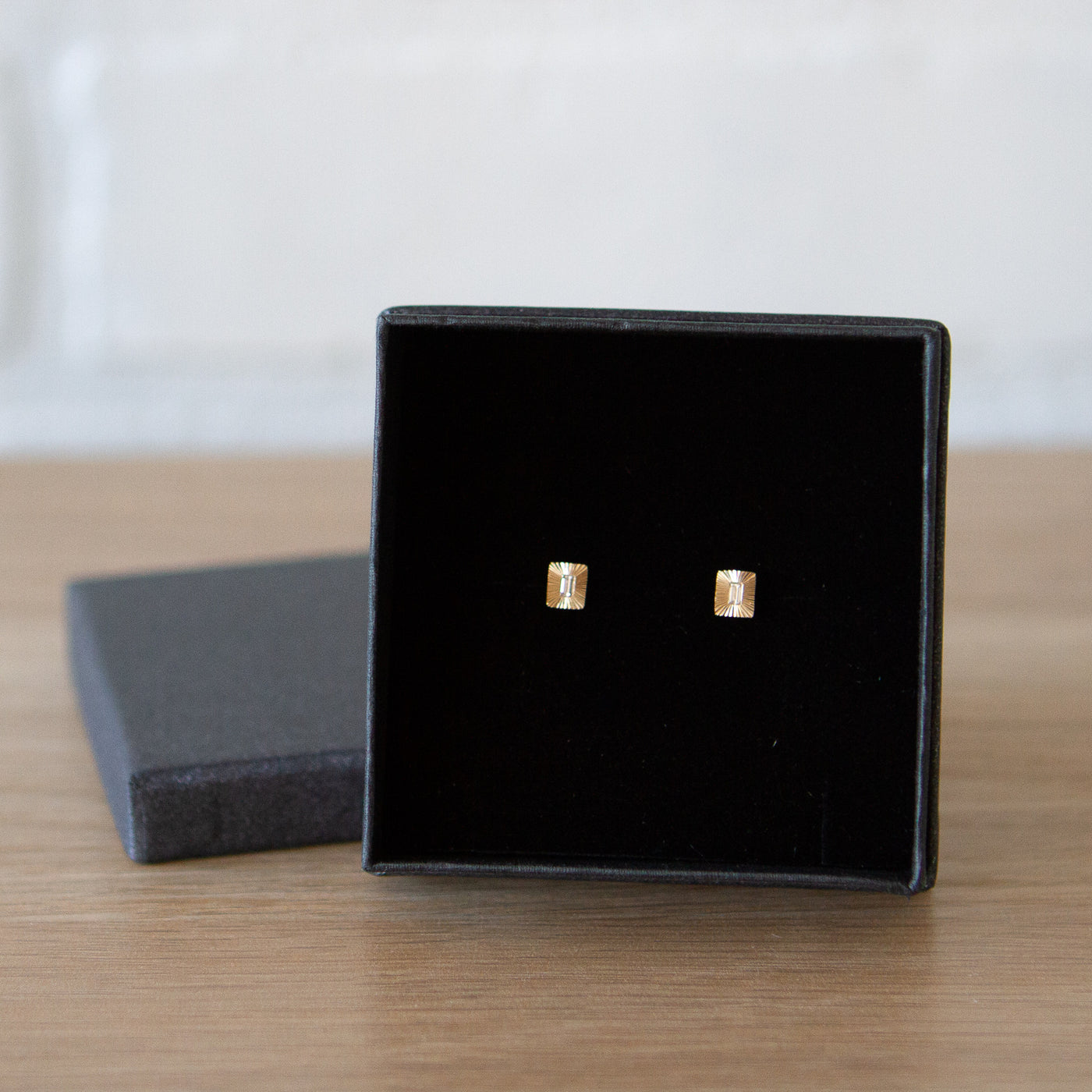 Rectangle 14k yellow gold Aurora stud earrings with baguette diamond centers and engraved rays in a gift box