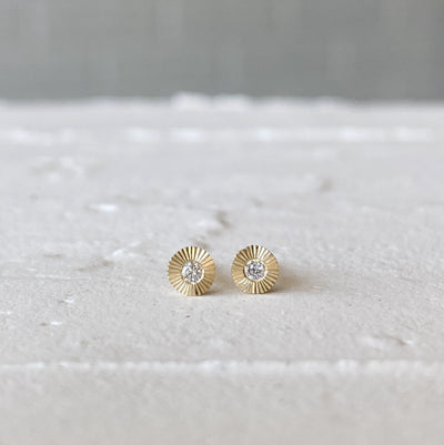 14k yellow gold micro aurora stud earrings with diamond centers and an engraved halo border in natural light