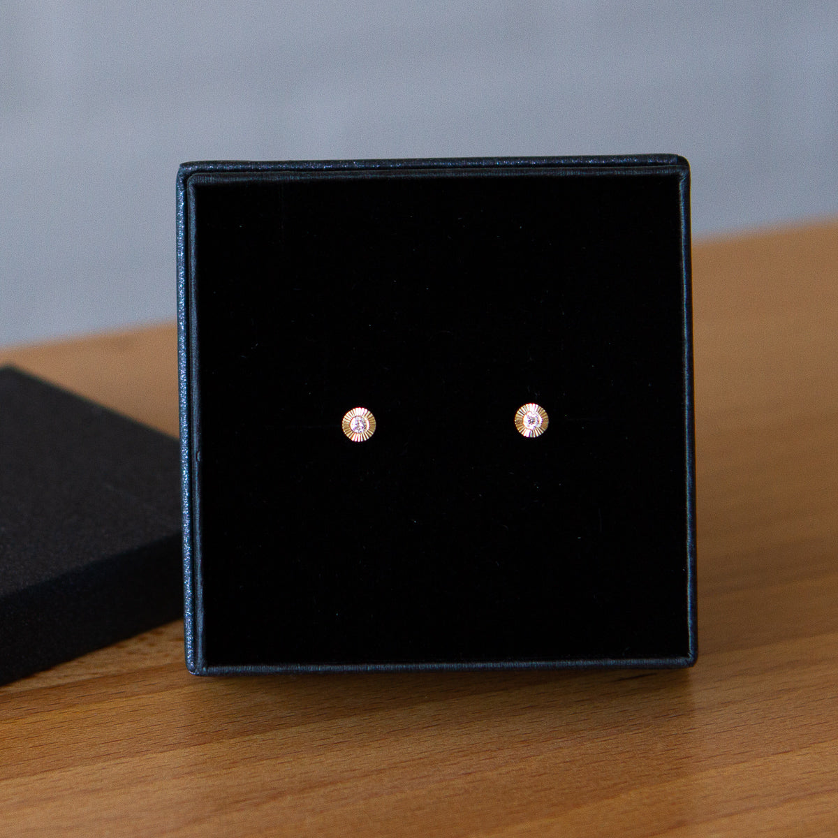 14k yellow gold small engraved Aurora stud earrings with white diamond centers in a gift box