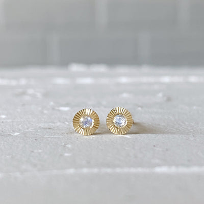 Small yellow gold Aurora engraved stud earrings with moonstone centers in natural light