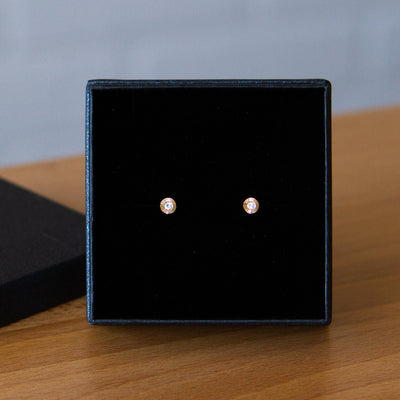Small yellow gold Aurora engraved stud earrings with moonstone centers in a gift box