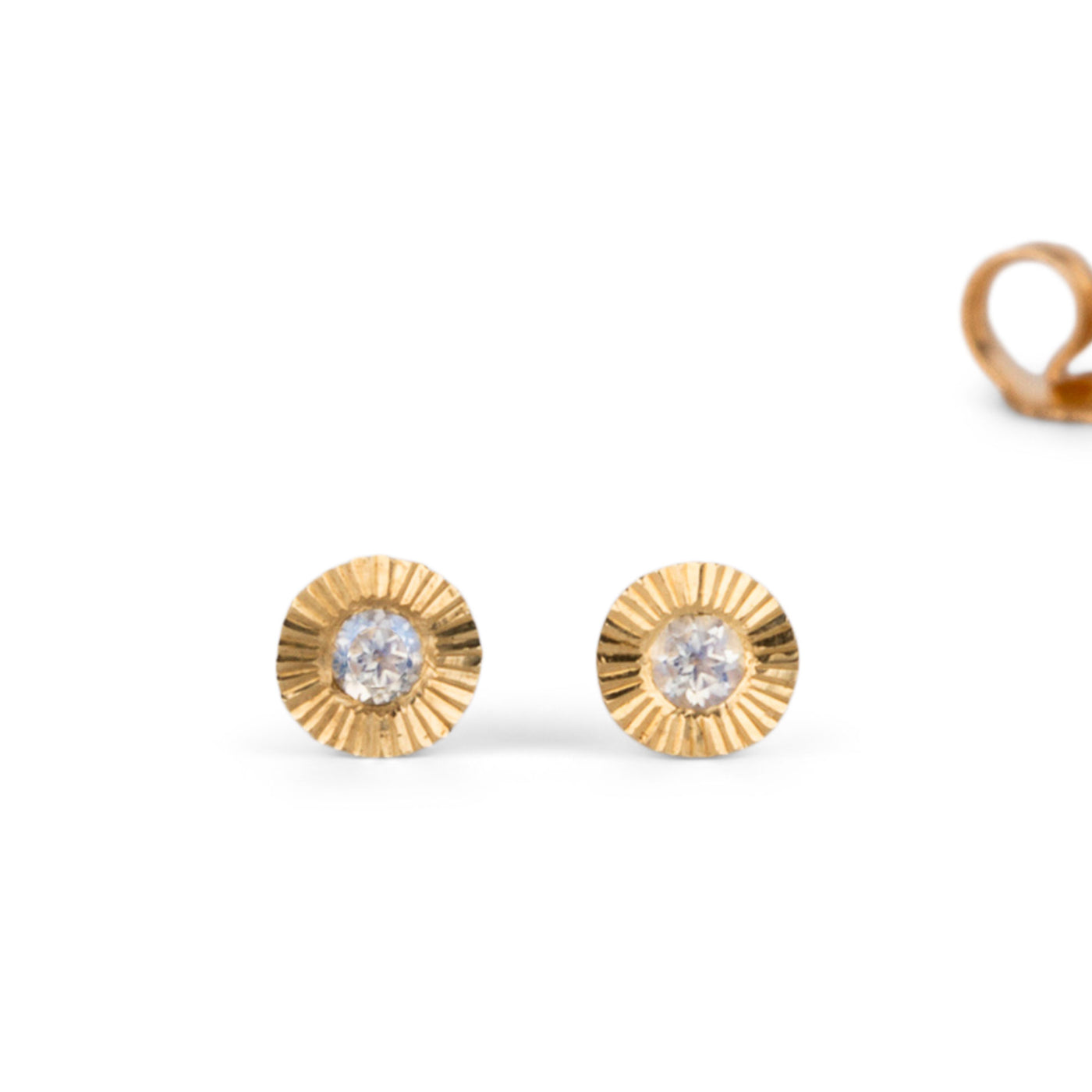 Small yellow gold Aurora engraved stud earrings with moonstone centers on a white background