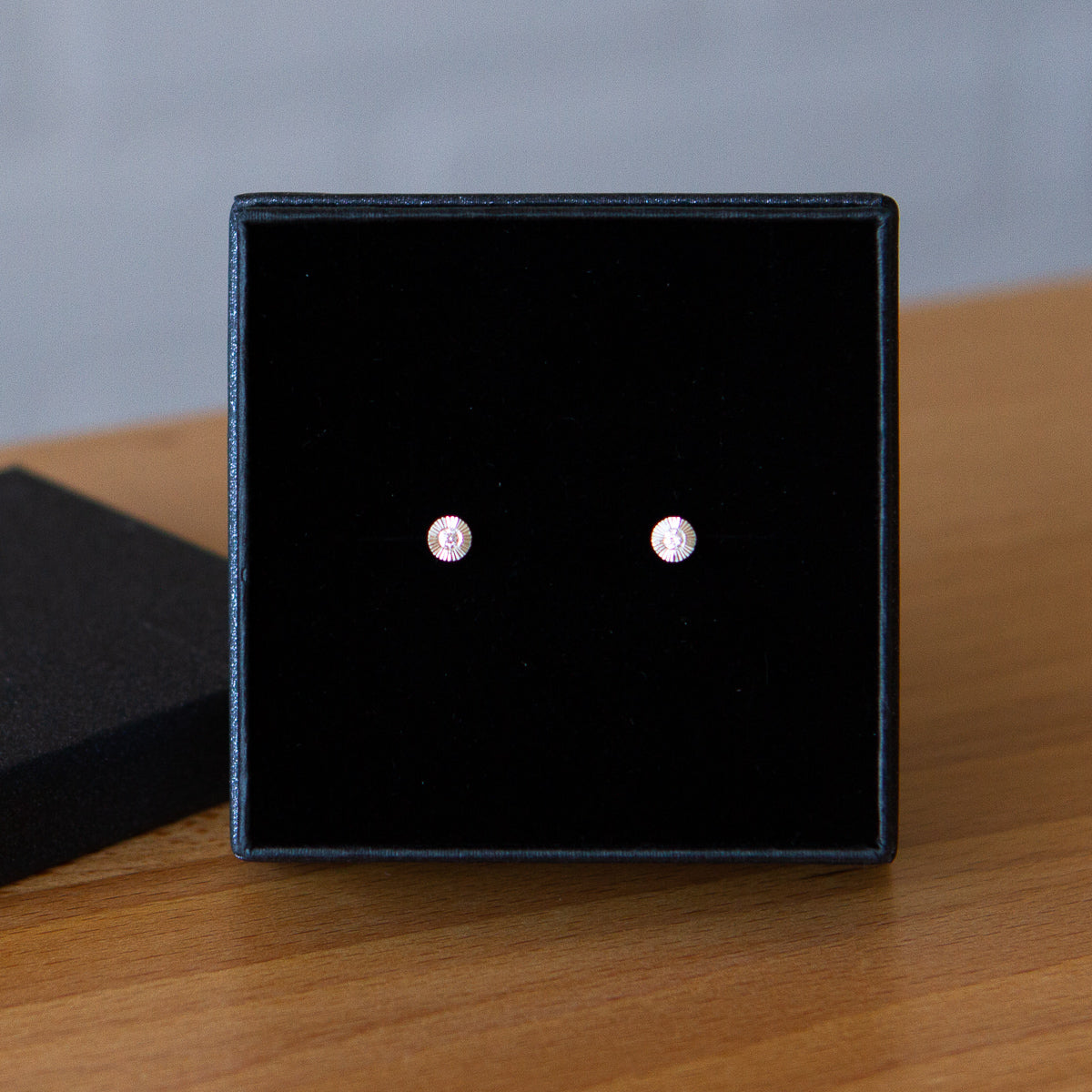 Sterling silver small engraved Aurora stud earrings with white diamond centers in a gift box