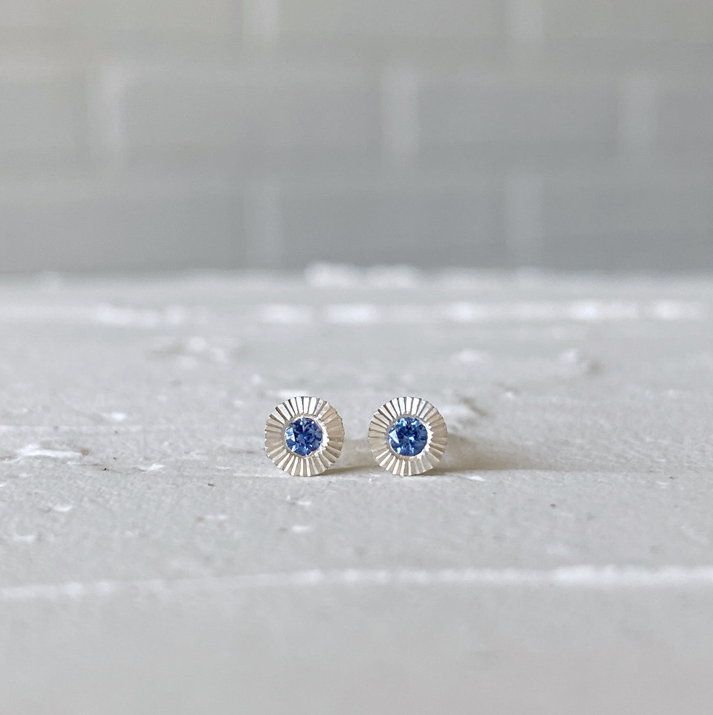 Sterling silver small engraved Aurora stud earrings with blue Yogo Montana Sapphires in natural light