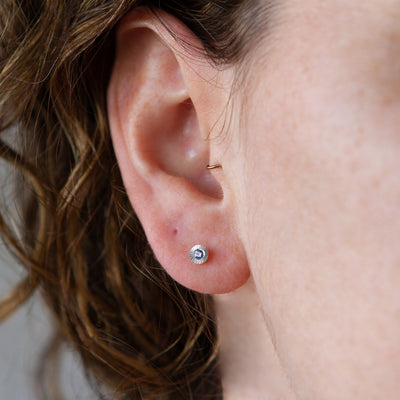 Sterling silver small engraved Aurora stud earrings with blue Yogo Montana Sapphires on an ear