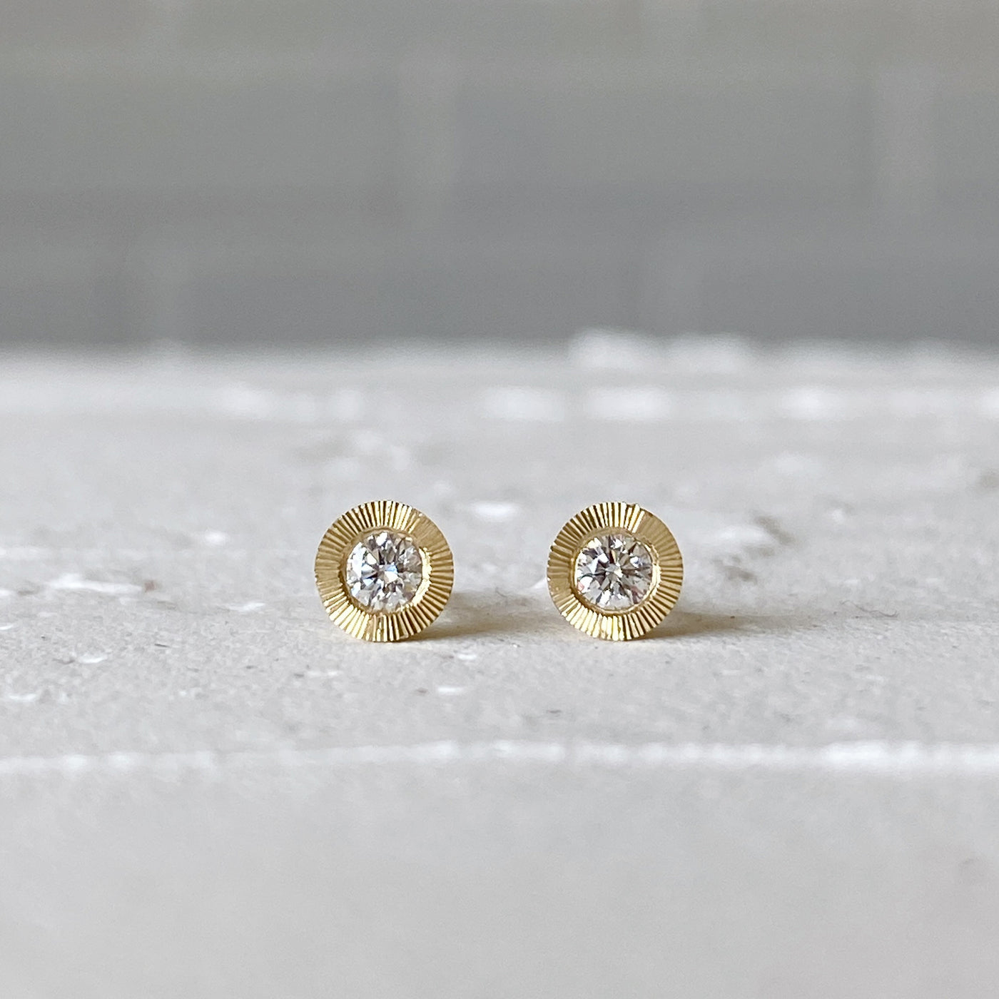 Medium Diamond Aurora stud earring in yellow gold with an engraved halo border in natural light