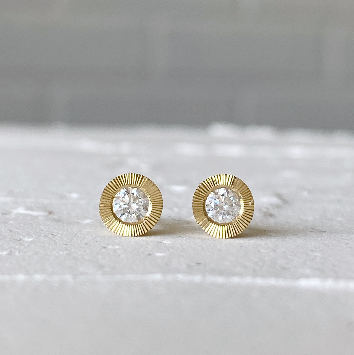 Large Diamond Aurora stud earring in yellow gold with an engraved halo border in natural light