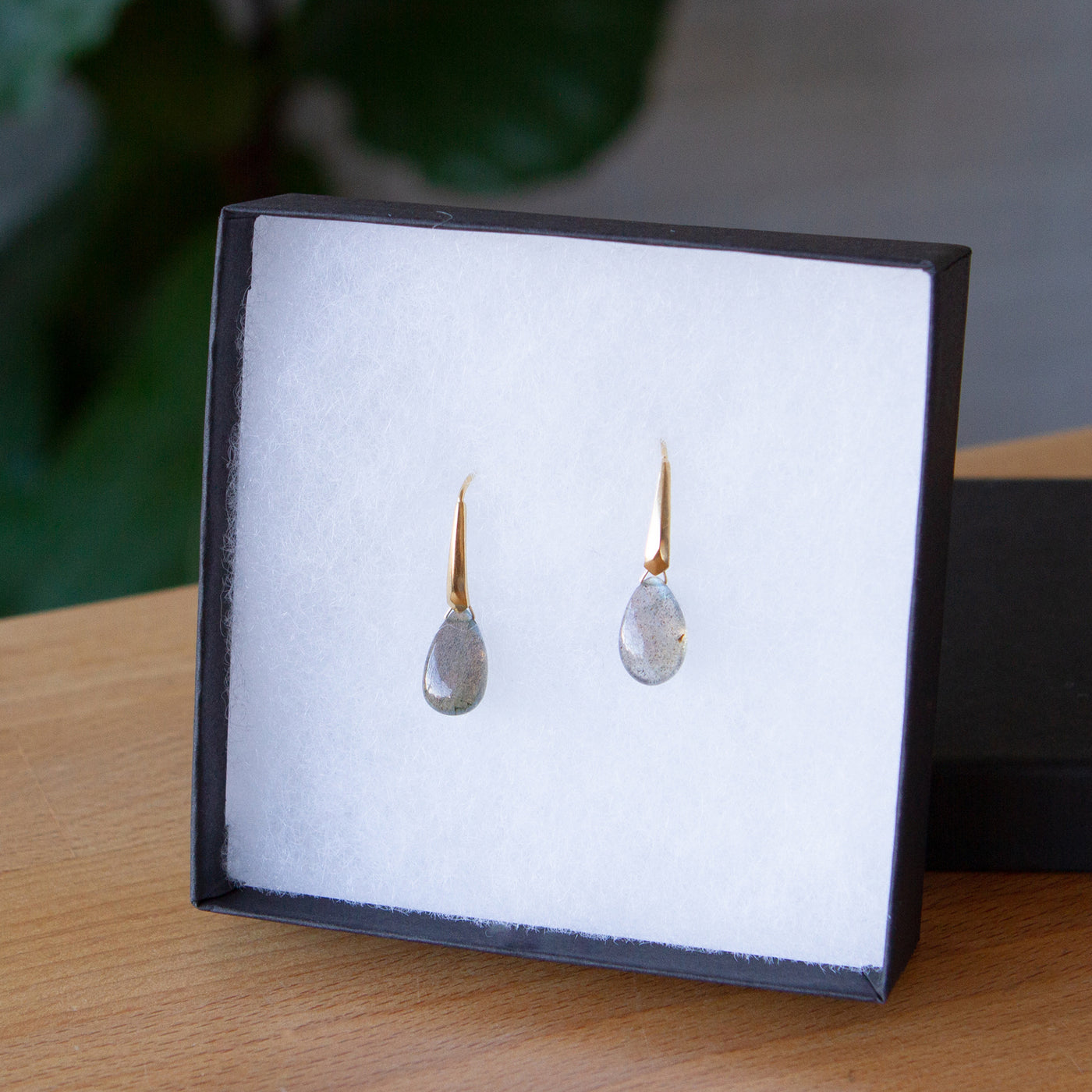 Labradorite earrings in gold vermeil propped up in a jewelry box on a wooden table