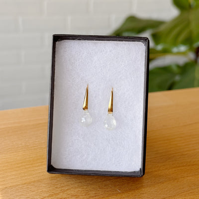 Moonstone earrings in gold vermeil propped up in a jewelry box on a wooden table