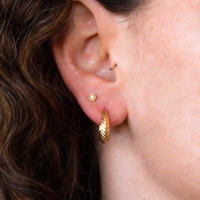  Hoop earrings with hinge closure and herringbone carved texture in vermeil on an ear