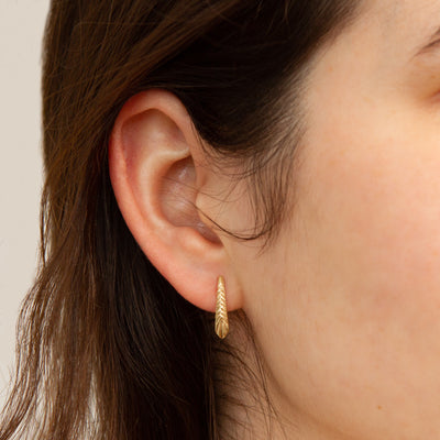 Yellow Gold Tapered Herringbone Stud Earrings modeled on an ear