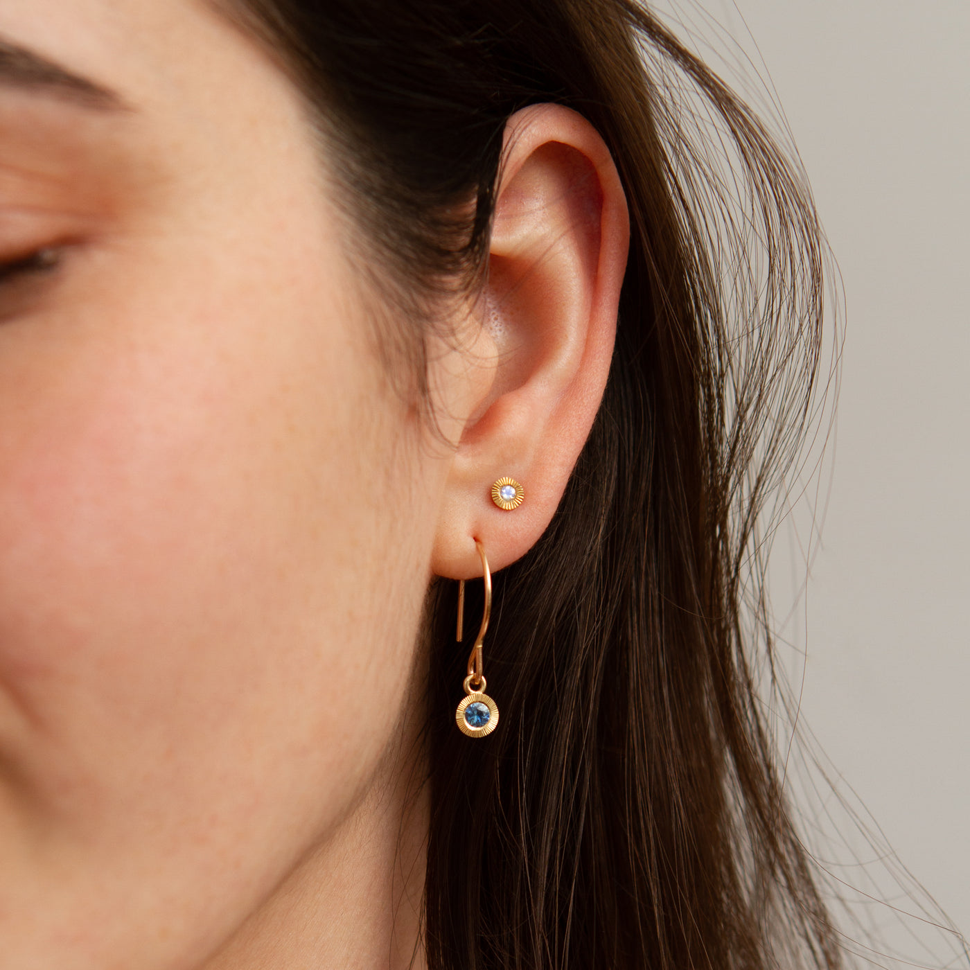 Small Aurora Moonstone Stud Earring in Yellow Gold modeled on an ear