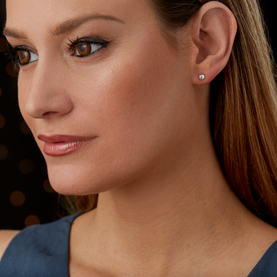 sterling silver micro size geometric faceted stud earrings with a single flush set diamond by Corey Egan on an ear
