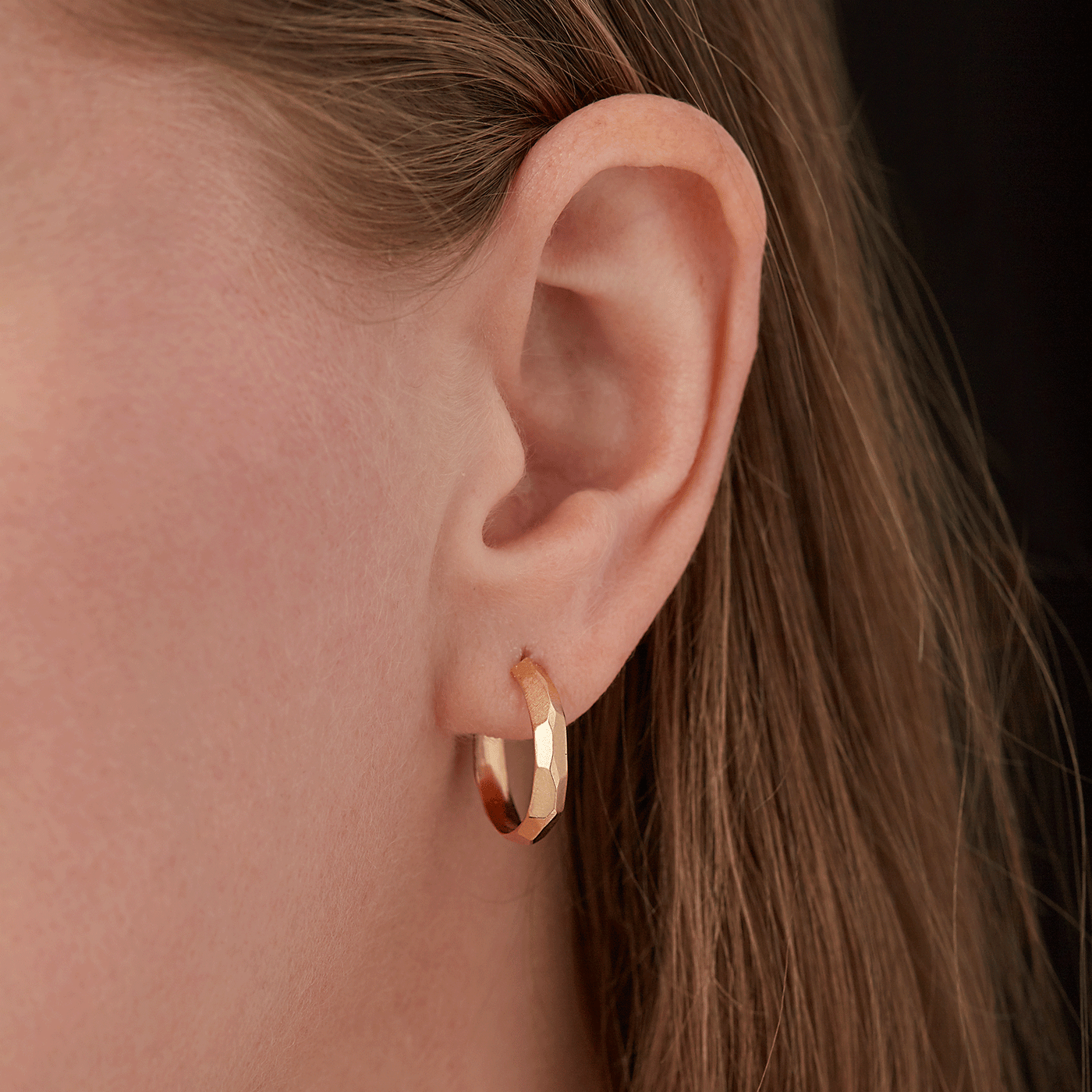 Gold Faceted Denali Hoop Earrings on an ear by Corey Egan