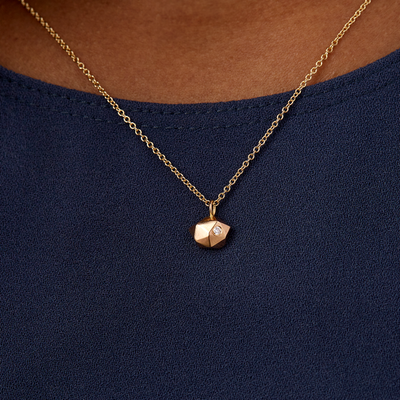 Faceted geometric gold tiny fragment necklace with a single white diamond in one facet on a neck | Corey Egan
