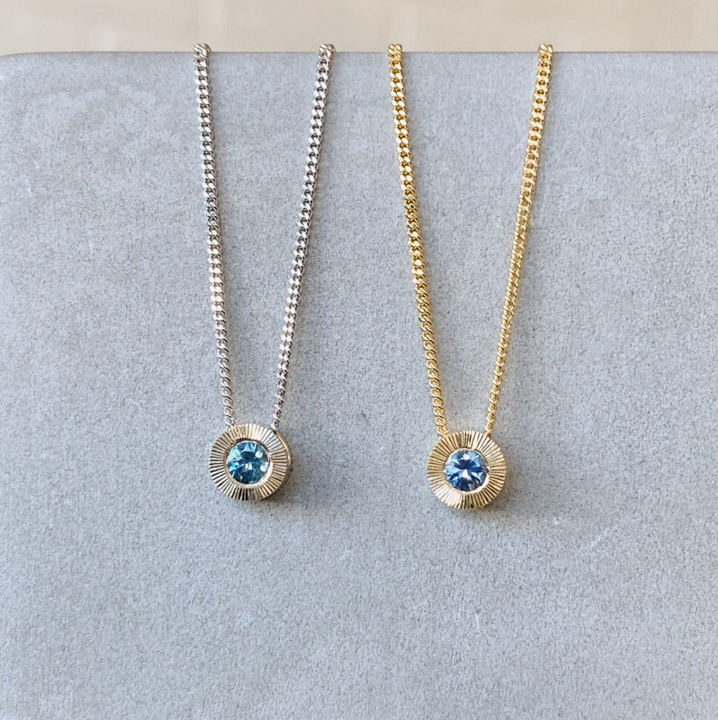Small aurora necklace with a blue montana sapphire center white gold on left and yellow gold on the right