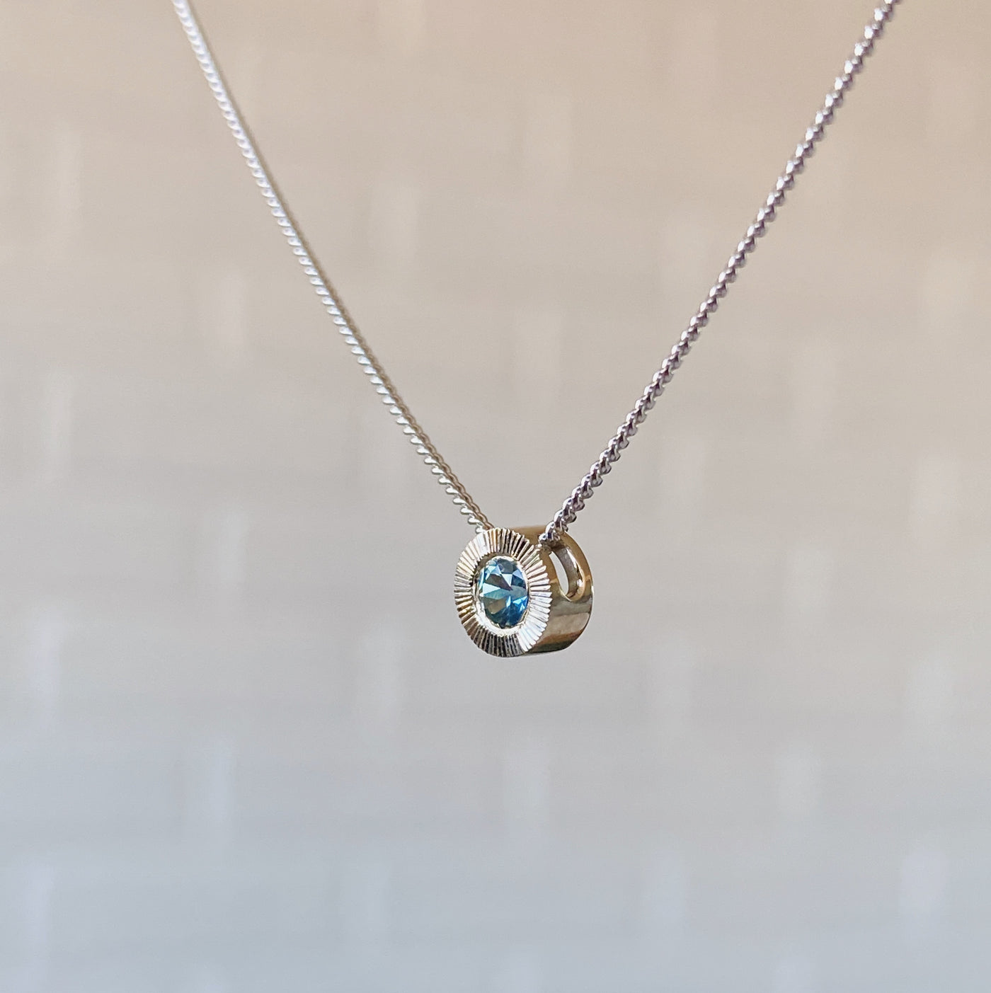 14k white gold small aurora necklace with a blue montana sapphire center side view