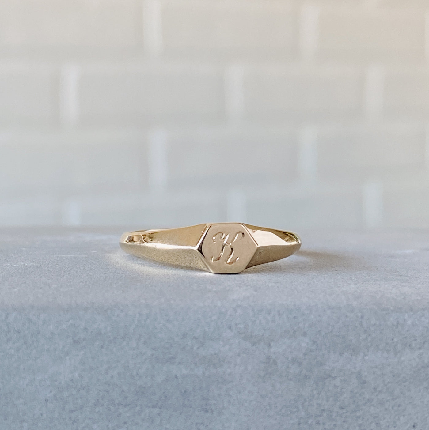 Low profile gold signet ring with hexagon top and engraved single script "K" initial