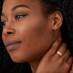 Yellow gold bar ring with three diamonds and a carved sunburst design around each by Corey Egan on a model