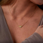 Triangular gold flash necklaw eith a diamond center and sunburst carved motif in 14k yellow gold around a neck by Corey Egan