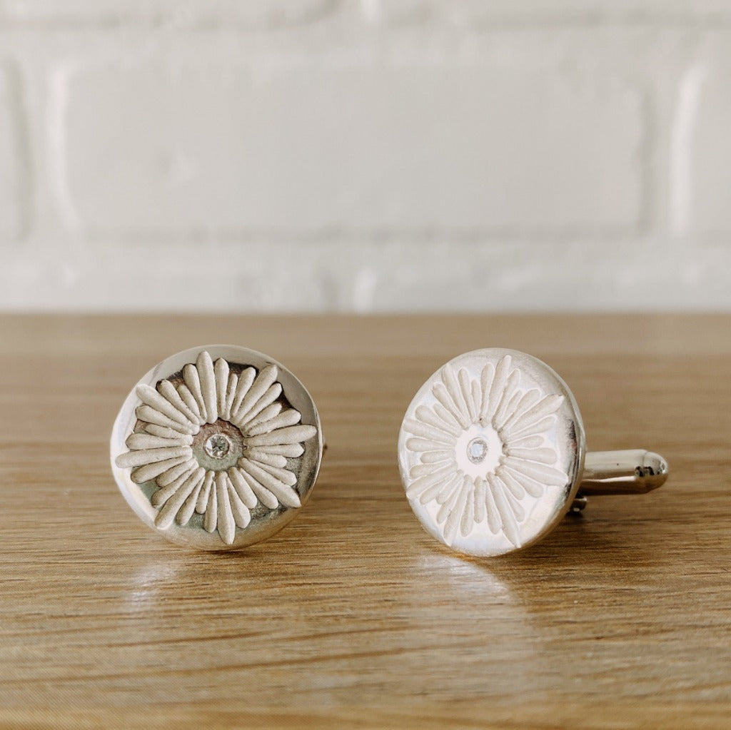 Sterling silver round cufflinks with a floral carved sunburst design and diamond centers