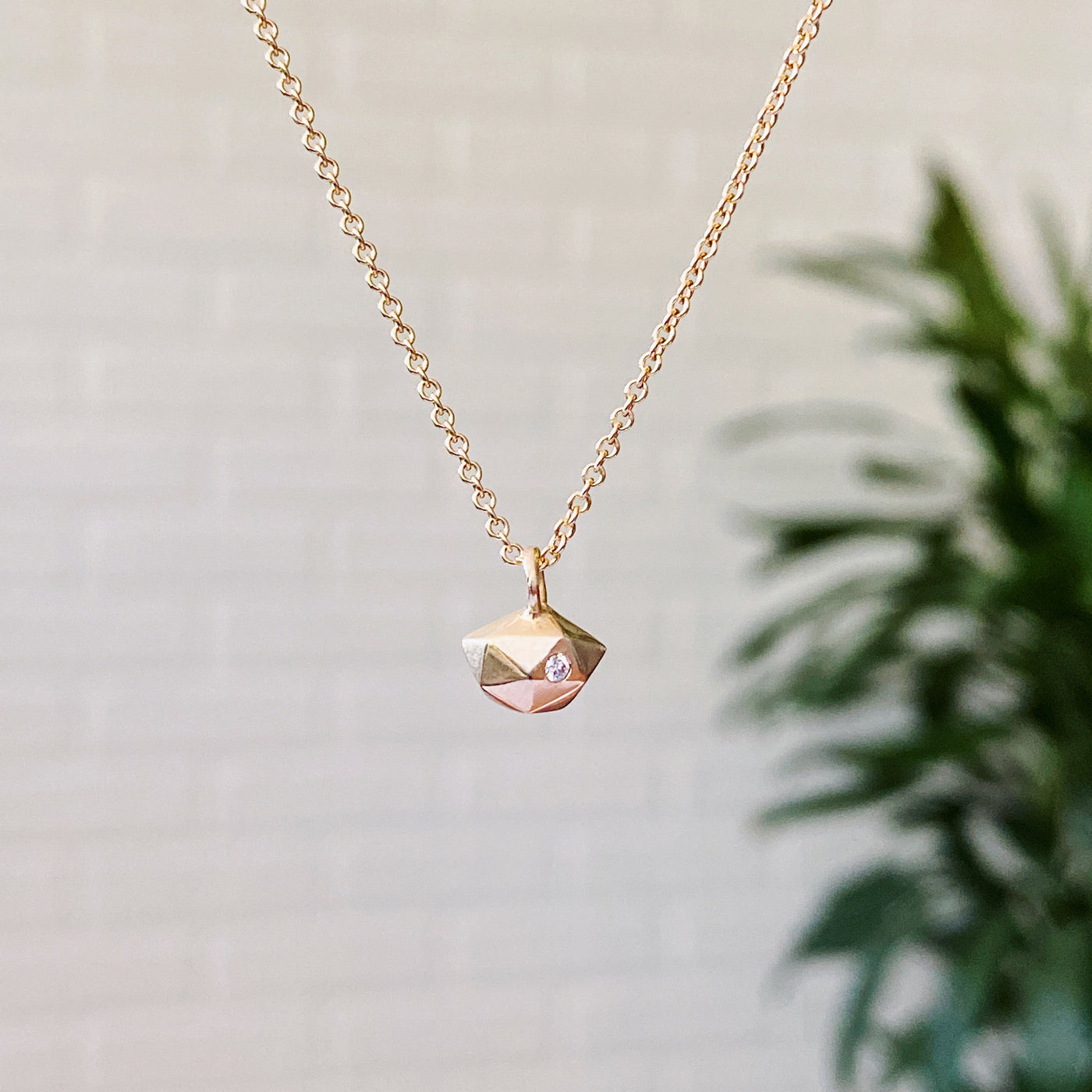 Faceted geometric gold tiny fragment necklace with a single white diamond in one facet in natural light | Corey Egan