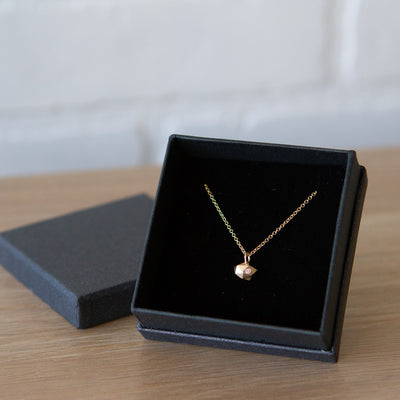 Faceted geometric gold tiny fragment necklace with a single white diamond in one facet in a gift box | Corey Egan