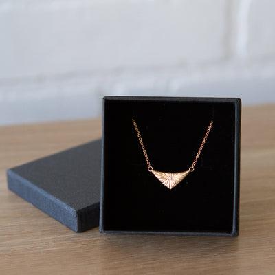 Triangular gold flash necklaw eith a diamond center and sunburst carved motif in 14k yellow gold in a gift box by Corey Egan