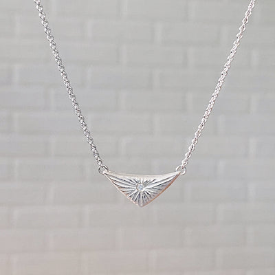Triangle silver sunburst necklace with diamond center in natural light by Corey Egan