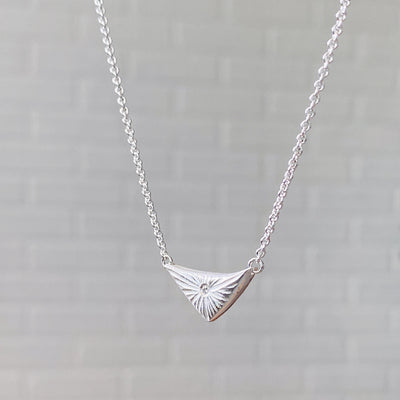Triangle silver sunburst necklace with diamond center side view in natural lightby Corey Egan