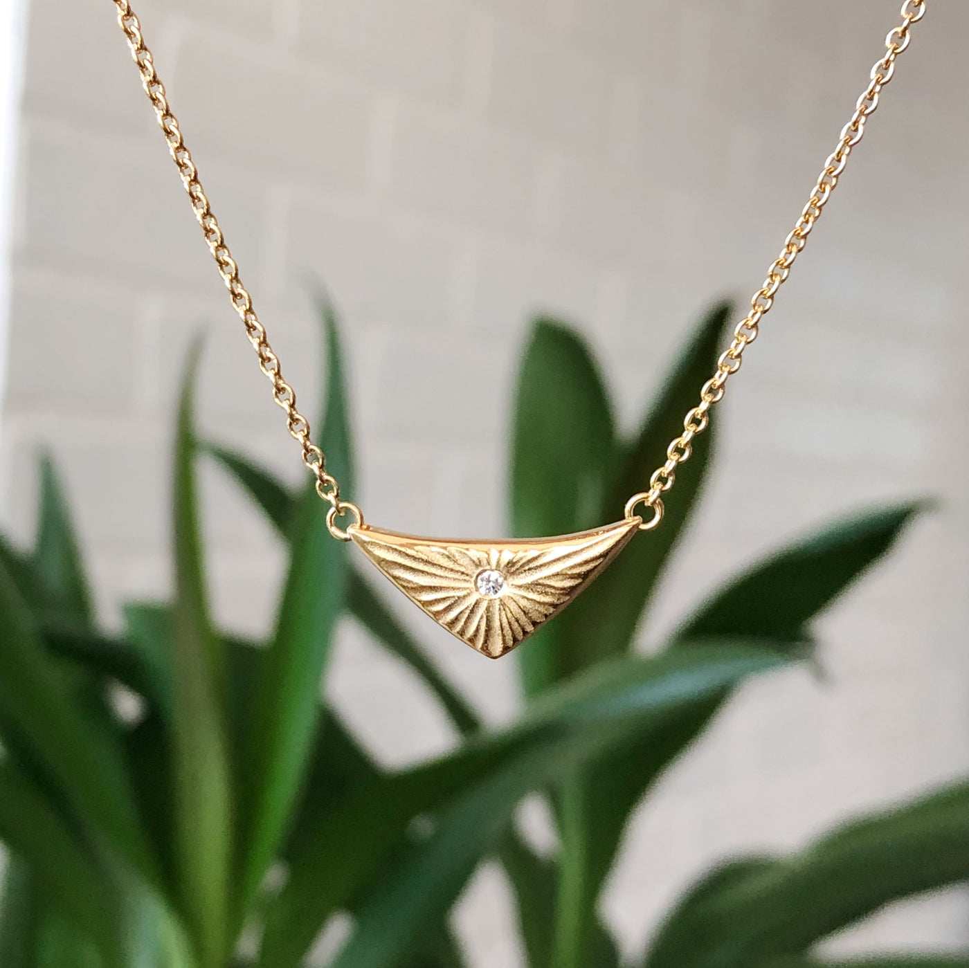 Flash triangular carved sunburst Vermeil Necklace with a diamond center in natural light by Corey Egan