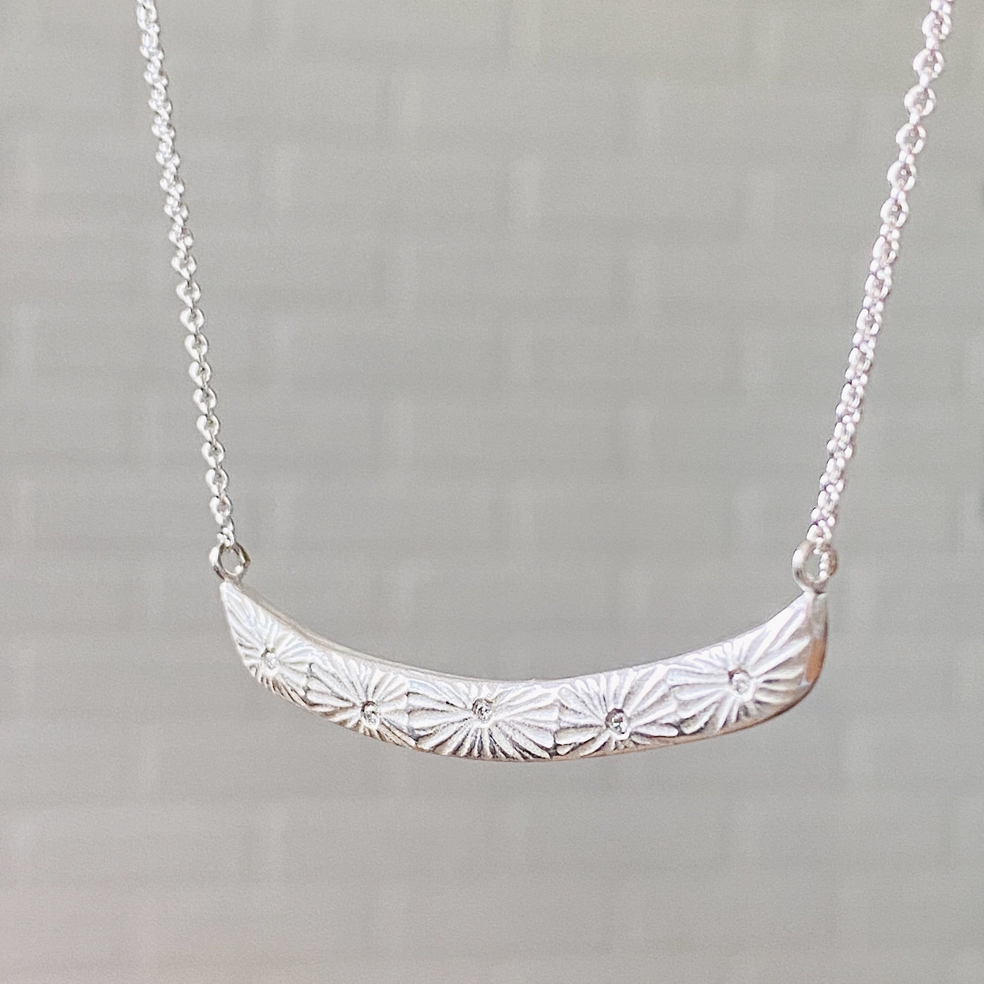 Sterling silver curved bar necklace with five scattered diamonds and an engraved sunburst pattern radiating from each side view | Corey Egan