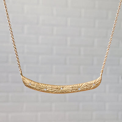 Curved bar necklace with five scattered diamonds and carved sunburst motif by Corey Egan