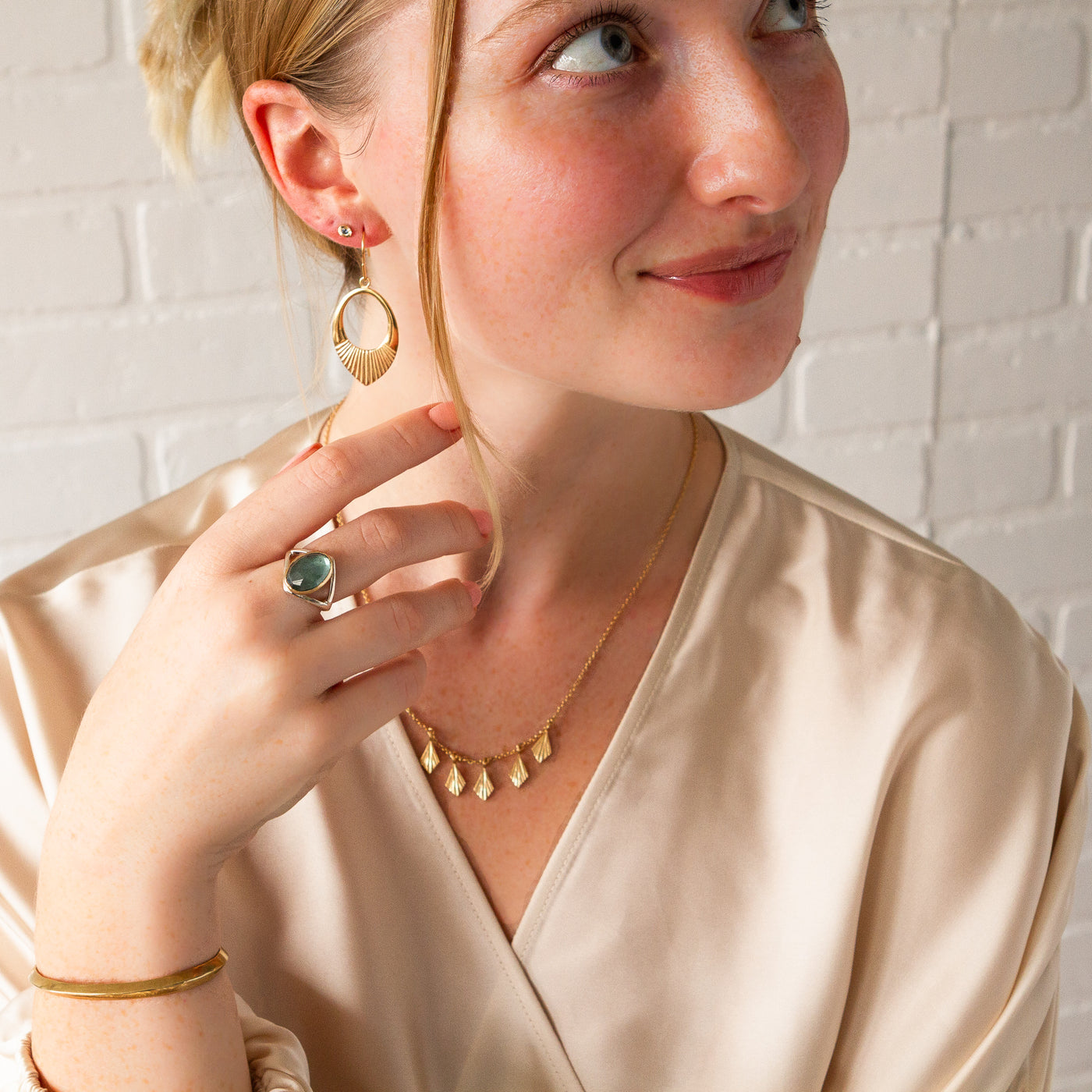 A model wearing the vermeil medium helios drop earrings with a moss aquamarine ring and the vermeil flame fan necklace