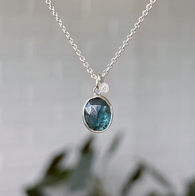 Moss Kyanite Silver Theia Necklace in front of a white wall, front angle 