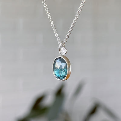 Moss Kyanite Silver Theia Necklace in front of a white wall, side angle