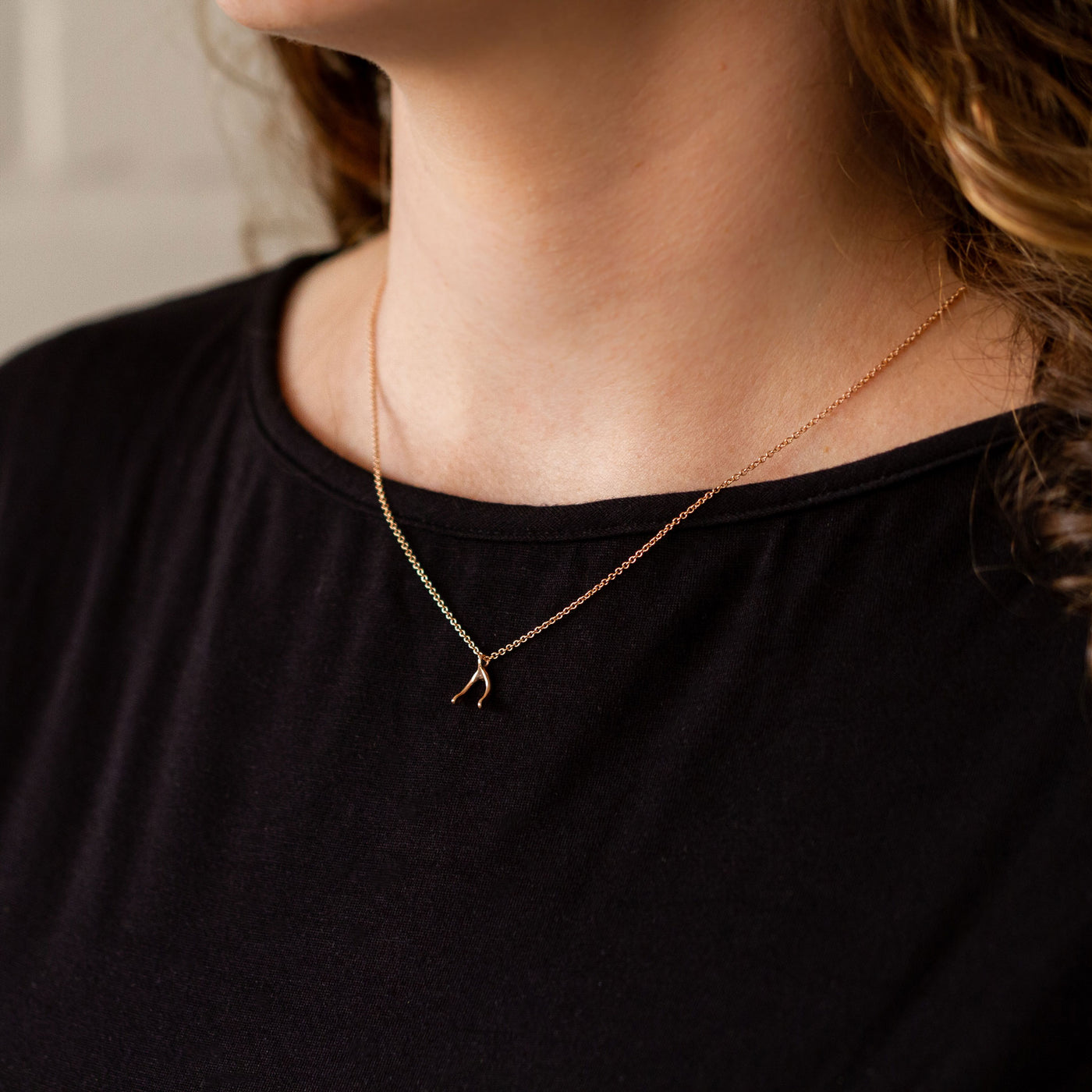 Rose Gold Wishbone Necklace around a neck