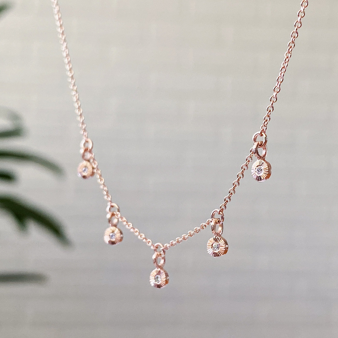 side view Rose gold and diamond station necklace with five tiny engraved pendants with diamond centers side view