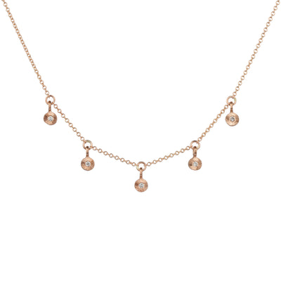 Rose gold and diamond station necklace with five tiny engraved pendants with diamond centers on a white background