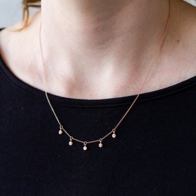 14k rose gold and diamond Rise station necklace by Corey EganRose gold and diamond station necklace with five tiny engraved pendants with diamond centers around a neck