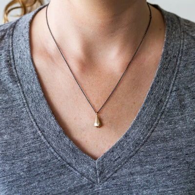 14k yellow gold faceted fragment pendant with a single diamond on an oxidized silver chain around a neck