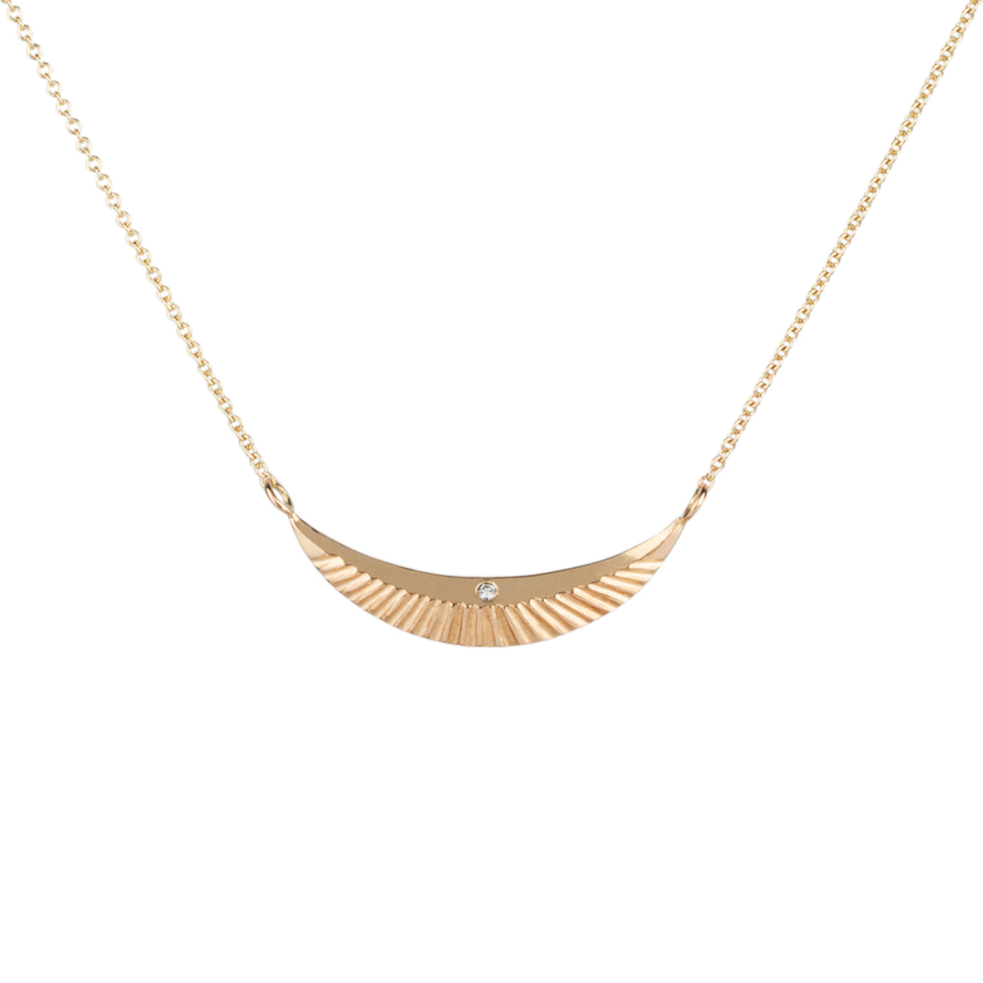 Gold crescent pendant with sunburst textured bottom and polished top and a single diamond. 