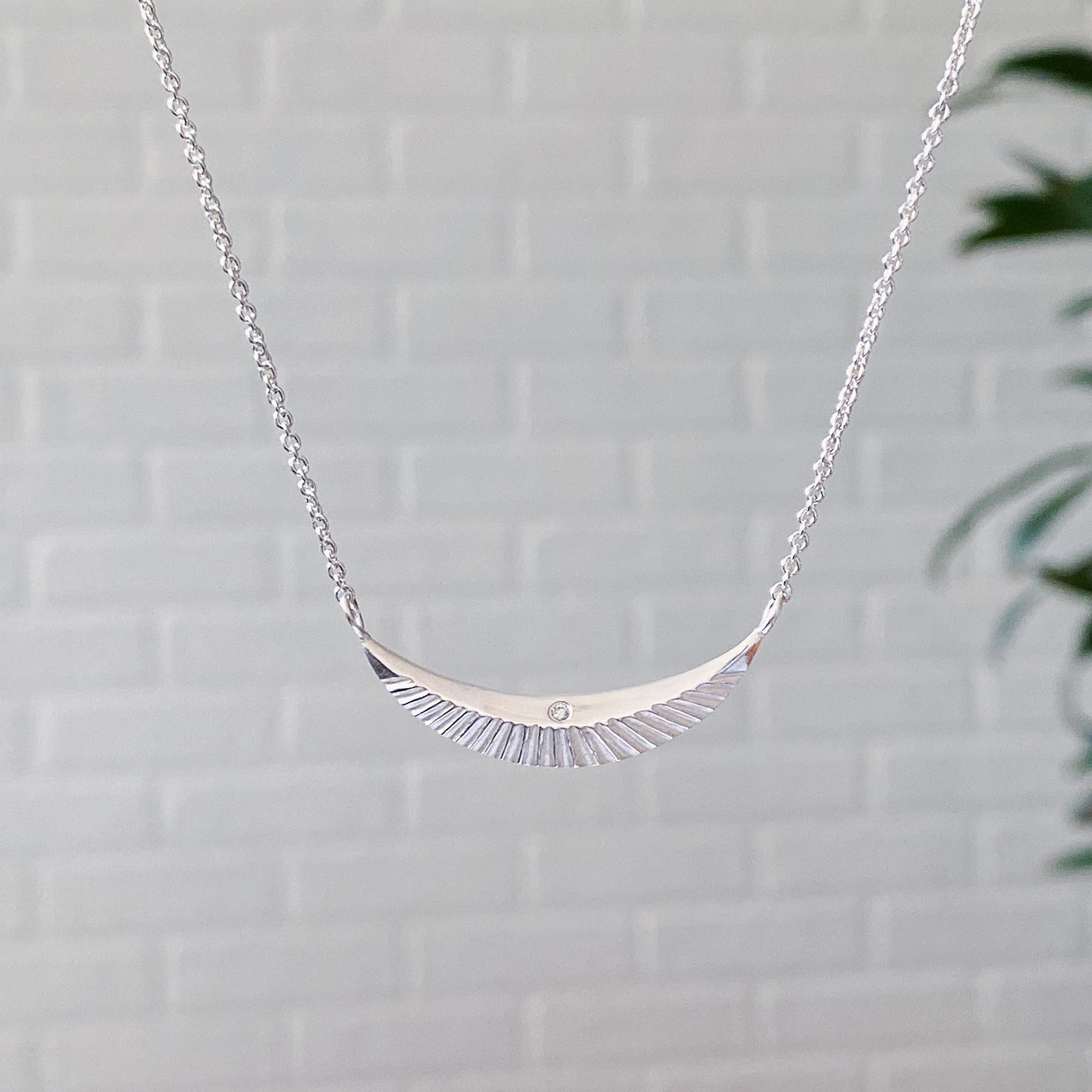 Crescent necklace with carved rays and a single diamond in sterling silver