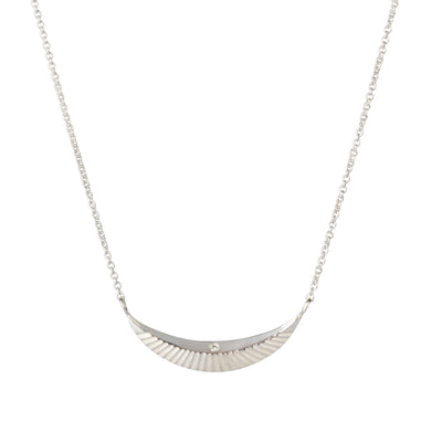 Crescent necklace with carved rays and a single diamond in sterling silver on a white background