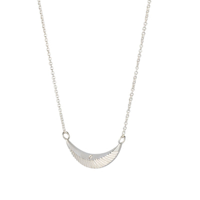 Side view of Crescent necklace with carved rays and a single diamond in sterling silver on a white background