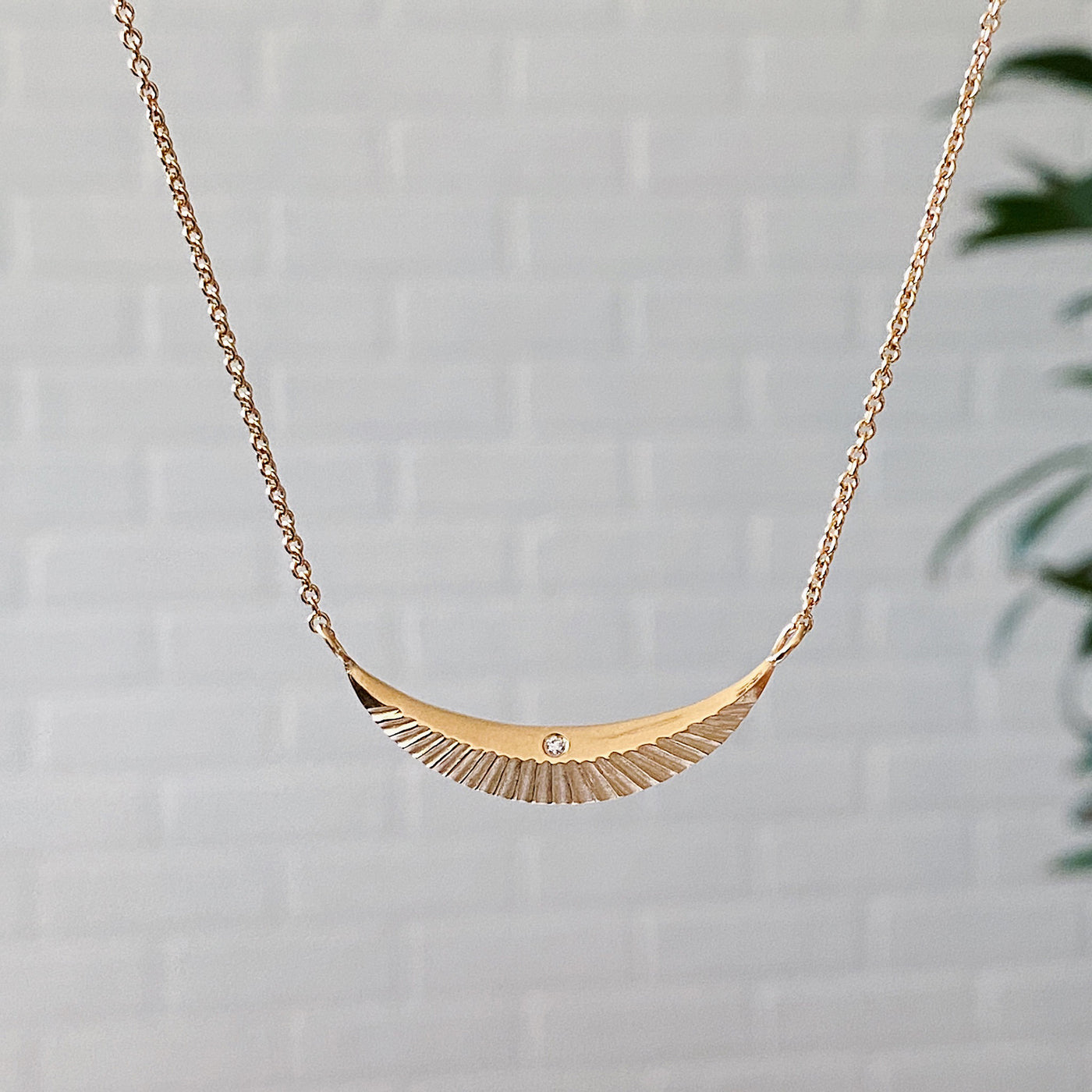 Crescent necklace with carved rays and a single diamond in vermeil 