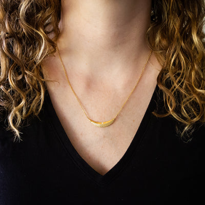 Crescent necklace with carved rays and a single diamond in vermeil  around a neck