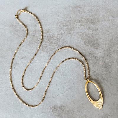 Ectra long neckalce with large open petal shape pendant with carved ray texture across the bottom
