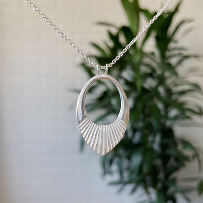 Silver medium open petal shape pendant with a textured bottom on a 22" silver chain