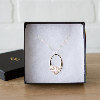 Silver medium open petal shape pendant with a textured bottom in a gift box